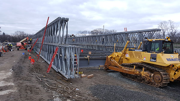 Ironworkers preparing a section of a temporary bridge structure which will be pushed into place by a Komatsu D155 dozer.